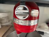 a red mixer with a metal bowl on the counter