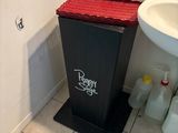 a black trash can sitting next to a white sink in a bathroom