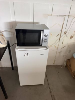 un micro-ondes posé sur un petit réfrigérateur, à côté d'une table