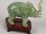 statue d'un éléphant posée sur un socle en bois, avec un fond blanc