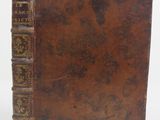 an old book with a brown cover sitting on top of a white surface