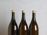 trois bouteilles de vin sont alignées sur une table en bois
