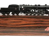 un train noir posé sur un socle en bois, sur fond blanc