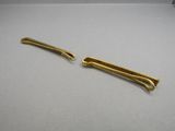 a pair of gold colored hair clips on a white surface