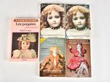 three books on a white table with a picture of a doll and a doll