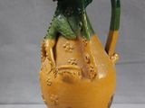 a yellow vase with a green handle on a table