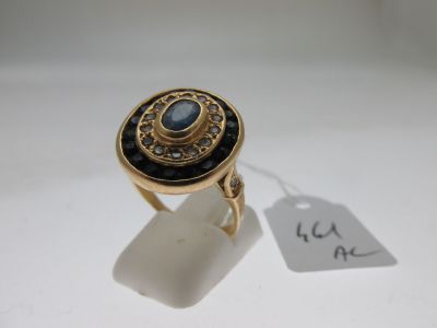 Gros plan sur une bague en or ornée d'une pierre bleue