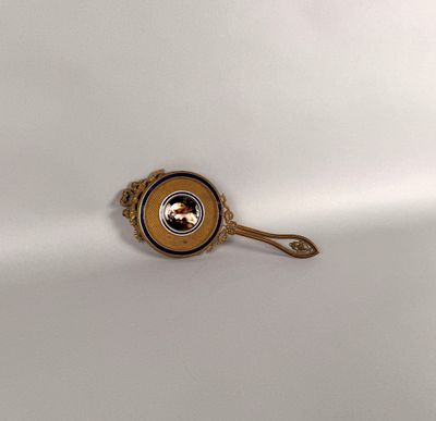 a gold spoon with a picture on it on a white surface