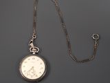 an antique silver pocket watch with a chain on a gray background