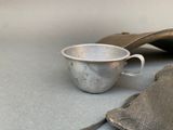 a silver cup sitting on a table next to a bag