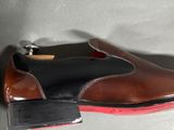 brown and black shoes with red soles on a white surface