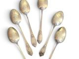 six silver spoons are arranged in a circle on a white surface