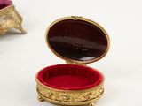 a small gold box with a red velvet inside