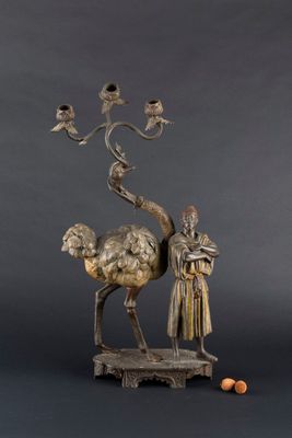 sculpture en bronze représentant un homme debout à côté d'un chameau sur le dos duquel se trouve un oiseau