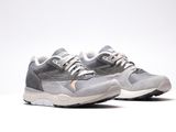 une paire de baskets grises et blanches posées sur une surface blanche