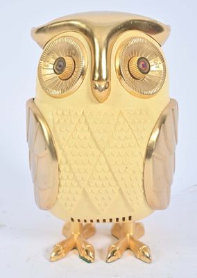 une figurine de chouette dorée posée sur une surface blanche