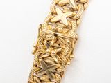 a close up of a gold bracelet on a white surface