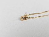 a gold necklace with a knot on it sitting on a white surface
