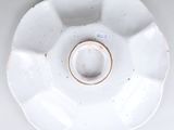 une assiette blanche à bord doré posée sur une table blanche