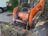 un petit tracteur orange garé sur un parking