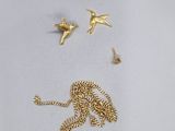 un collier en or et deux oiseaux sur un fond blanc
