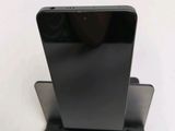 the back of a black cell phone sitting on top of a metal stand