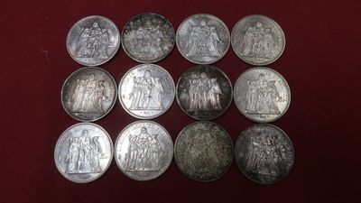six different types of silver coins on a red surface