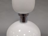 un gros plan d'une lampe de table blanche posée sur une surface grise