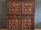 an old wooden cabinet with carved doors and drawers on a wooden floor