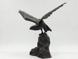 statue of an eagle perched on a rock on a white background