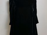 black velvet dress on a mannequin stand against a white wall