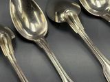 cinq cuillères et deux cuillères posées sur une table