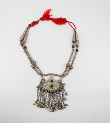 a silver necklace with a red tassel and beads