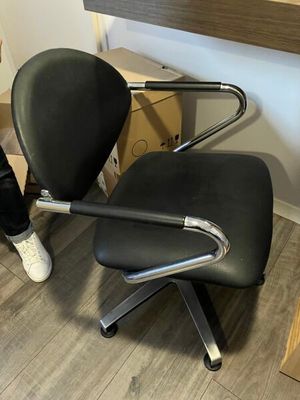 une personne debout à côté d'une chaise noire dans une pièce