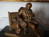 une statue en bronze représentant un homme assis sur un banc