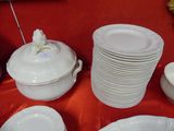 many plates and bowls on a table with a red table cloth