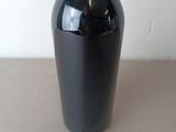 a black vase sitting on a table with a white wall in the background