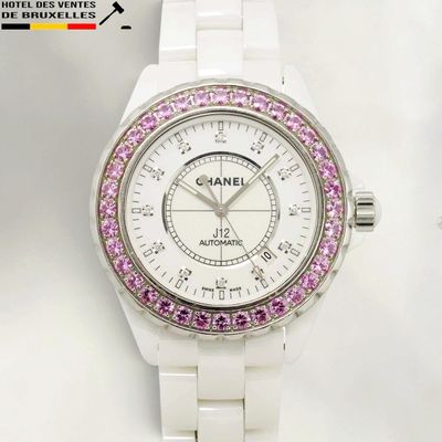 a close up of a white watch with pink crystals on it