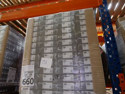 une grande pile de cartons dans un entrepôt, sur laquelle est apposée une étiquette de prix