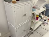 a white cabinet in the corner of a room with a computer on top