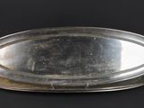 an oval silver tray on a black background with a black background