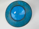 a blue plate on a white table with a sky in the background