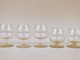 six verres à vin vides alignés sur une surface blanche