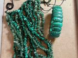 green necklaces and bracelets are displayed in a box on a table