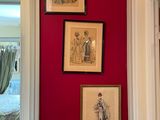 three framed pictures on the wall of a red room
