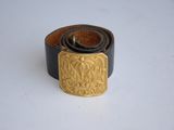 leather belt with a gold buckle on a white surface