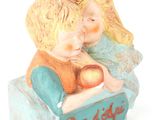 une figurine représentant un garçon et une fille tenant une pomme