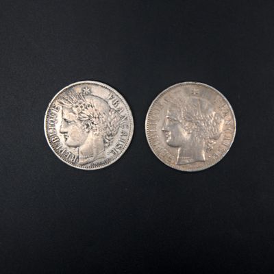 two silver coins on a black surface, one of which has a woman ' s head and the other of