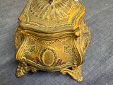 an antique brass box with a lid on a blue carpet