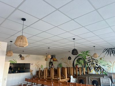 des tables et des chaises dans un restaurant où est accroché un grand tableau au mur